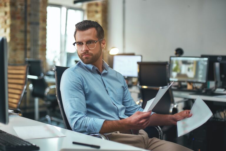 Working day. Busy and focused bearded man in eyeglasses and formal wear holding documents and